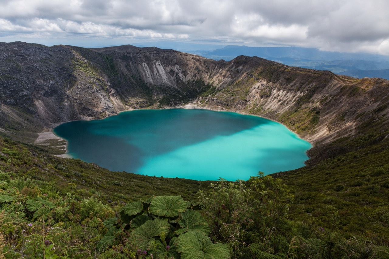 The turquoise sulfuric crater lake of Santa Ana Volcano seen from the rim with steam drifting across the surface